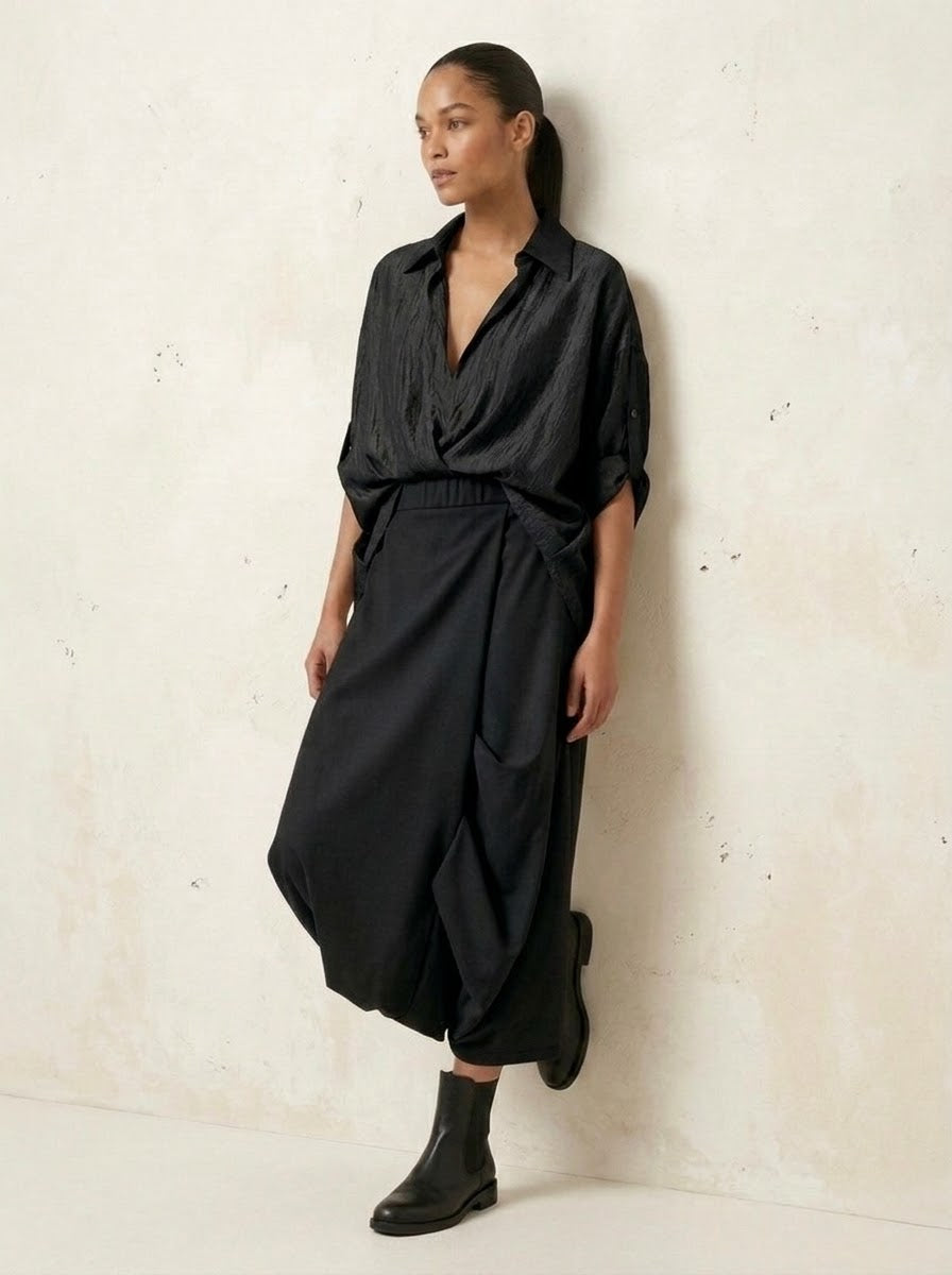 Model wearing black Roberta harem trousers, relaxed three-quarter pose