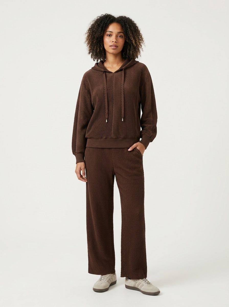 Model wearing Sunday pleated trousers in chocolate with matching hooded top