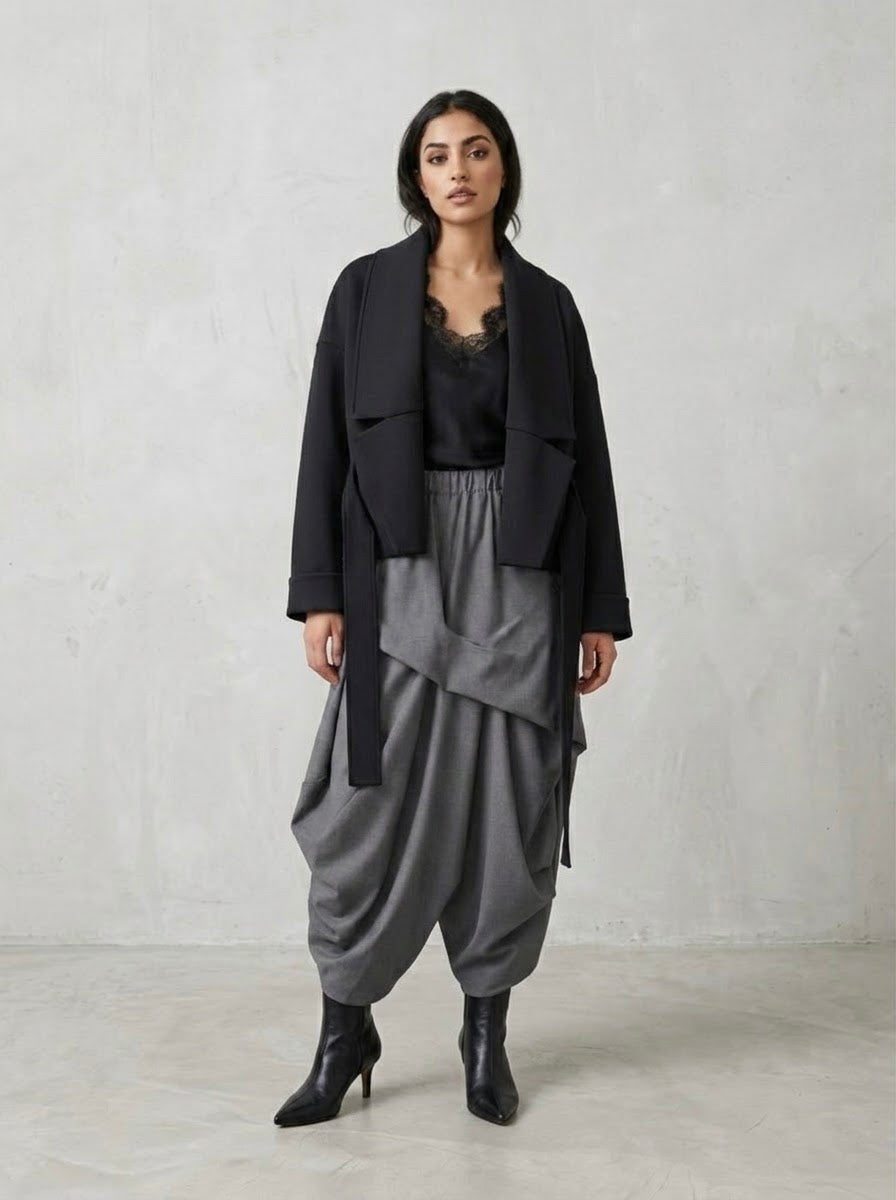 Model wearing the Izobel black scuba jacket open over grey harem trousers