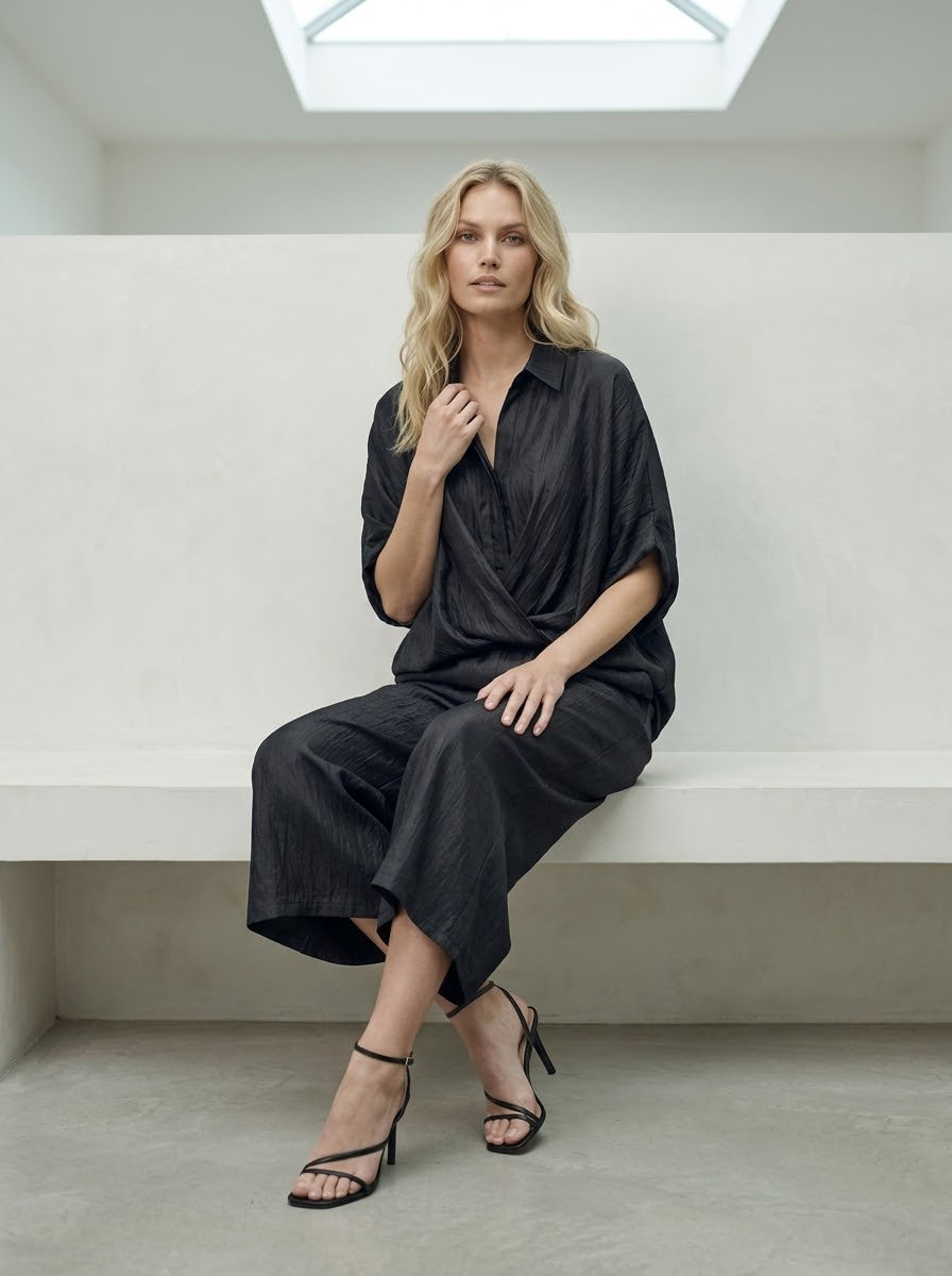 Model wearing black Lavender shimmer trousers with matching shirt, seated view