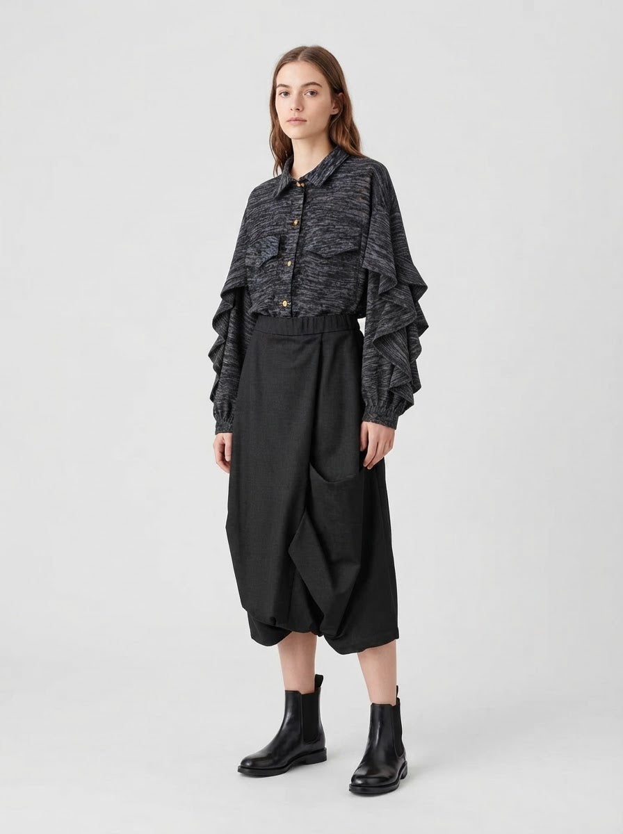 Model wearing the grey Capelini frill sleeve blouse tucked into black trousers