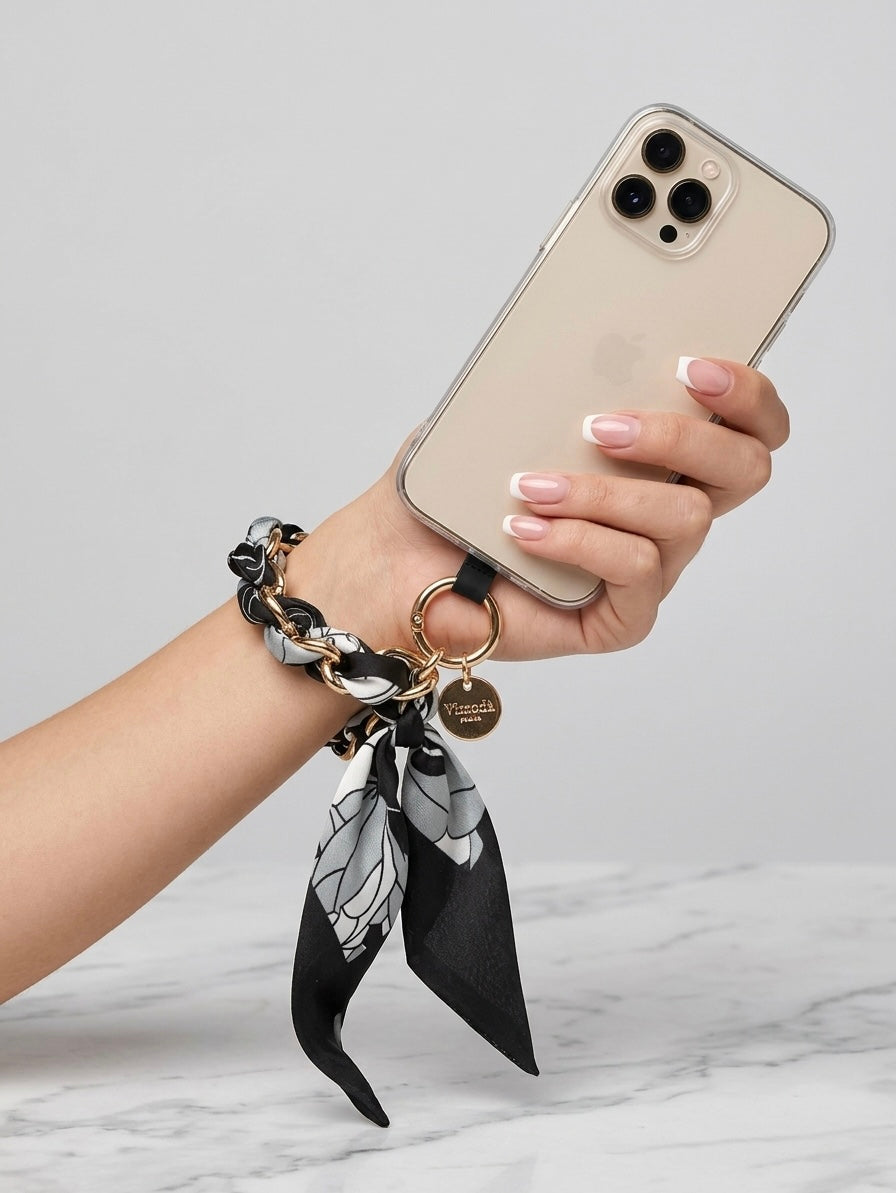 Black Sandi scarf print phone wrist strap worn around the wrist and attached to a phone case