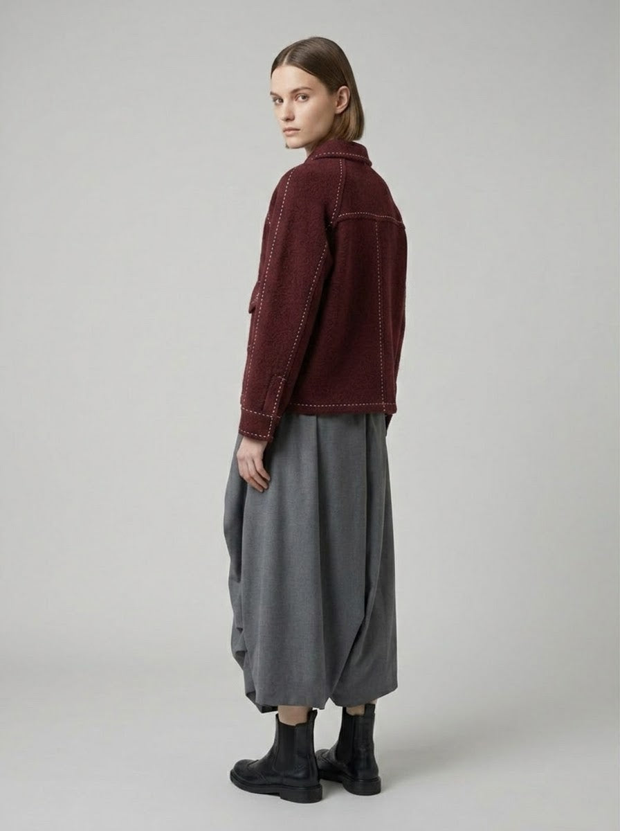 Model wearing Sara saddle stitch knitted jacket in burgundy, back three-quarter view