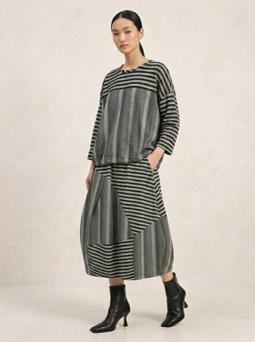 Model wearing the Elisa grey varied-stripe T-shirt with a coordinating patchwork skirt