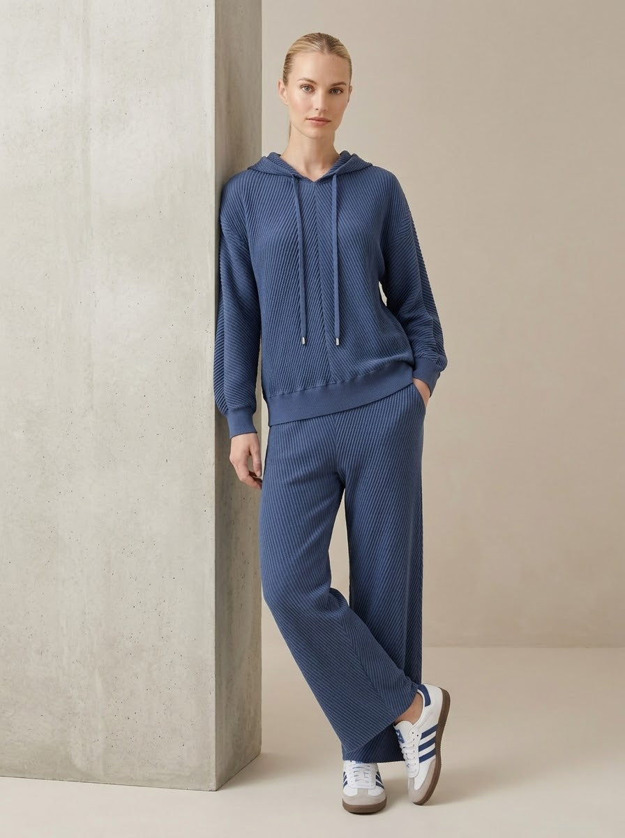 Model wearing Sunday pleated trousers in navy with matching hooded top