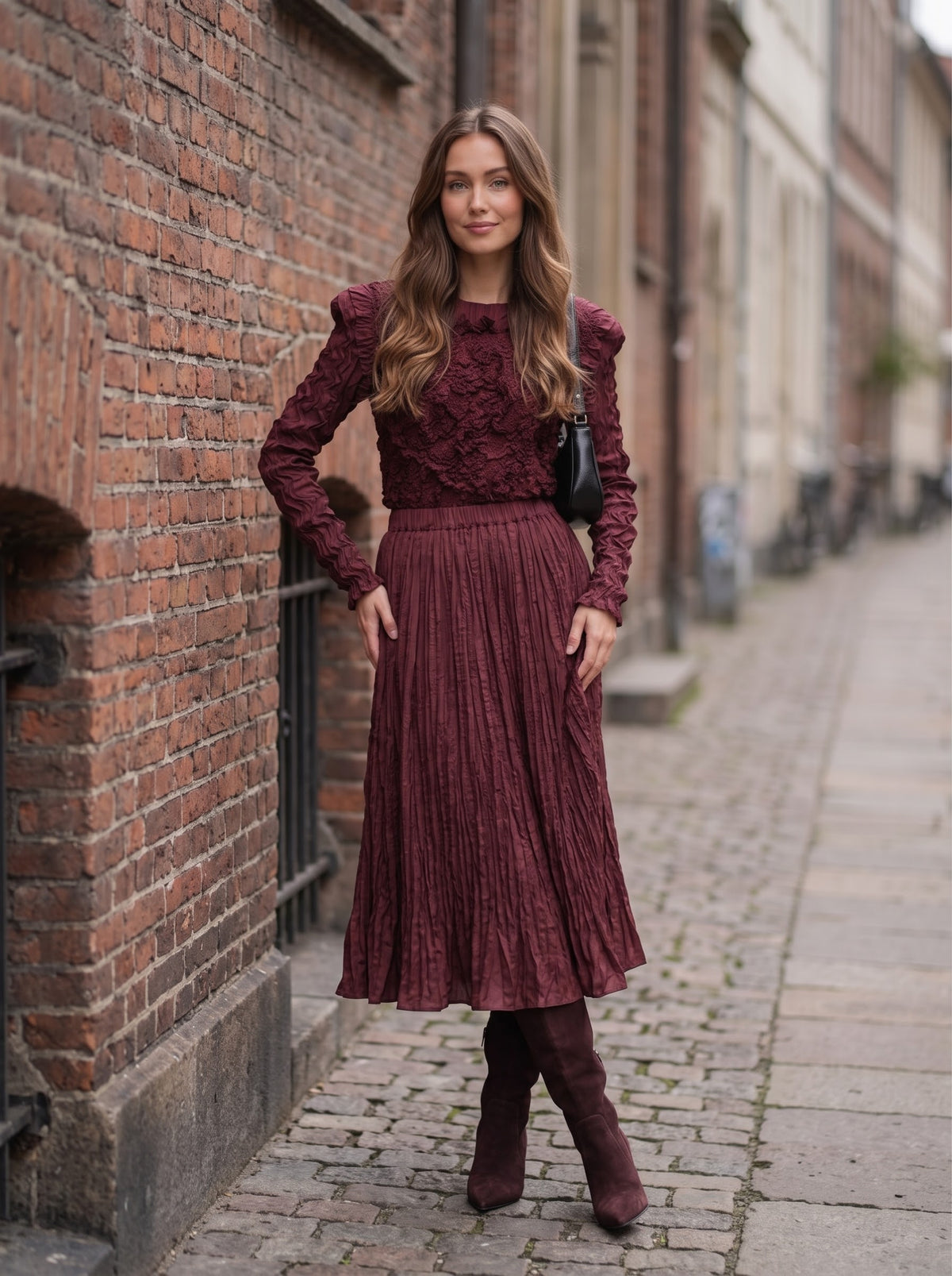 Model beside a brick wall in Emma burgundy Confetti Top and matching flared skirt, with the skirt waistband visible.