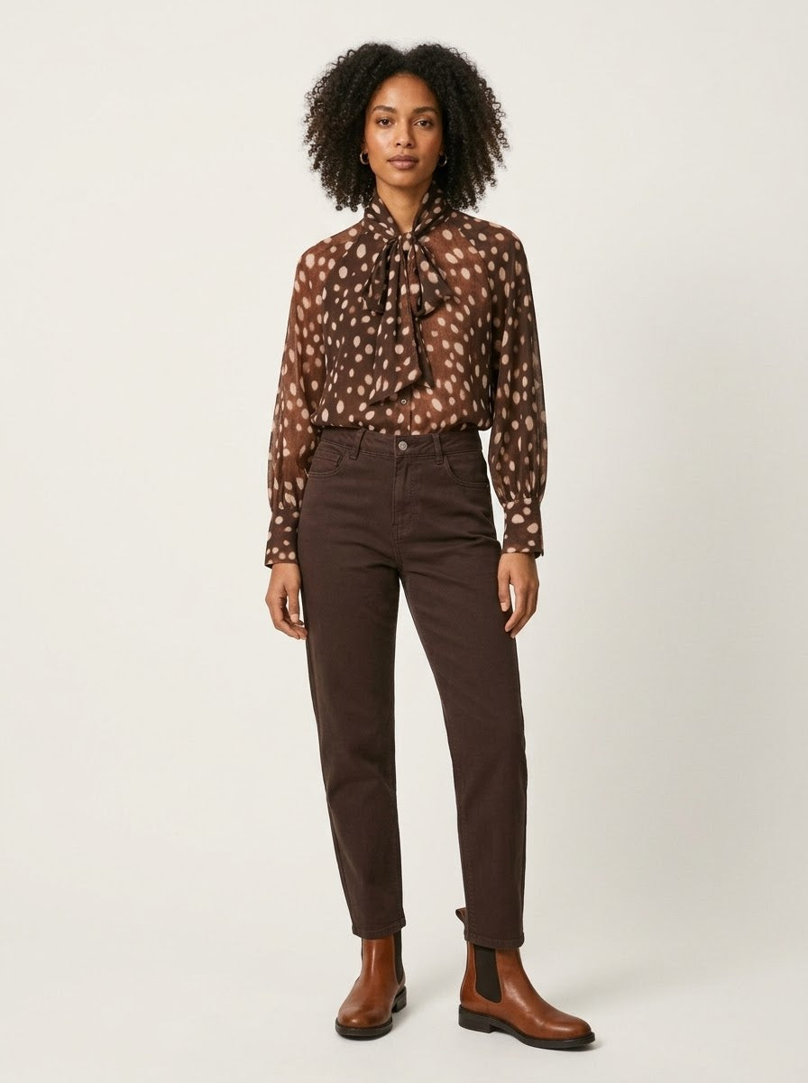 Model wearing tan Judith spot bow blouse tucked into trousers