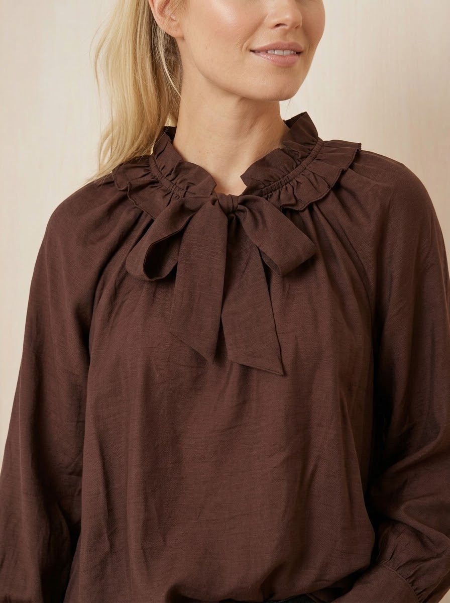 Close-up of Ariel chocolate frilled self-tie neckline