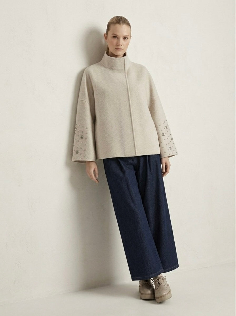 Model wearing cream Soraya wool blend cape jacket with dark wide-leg trousers