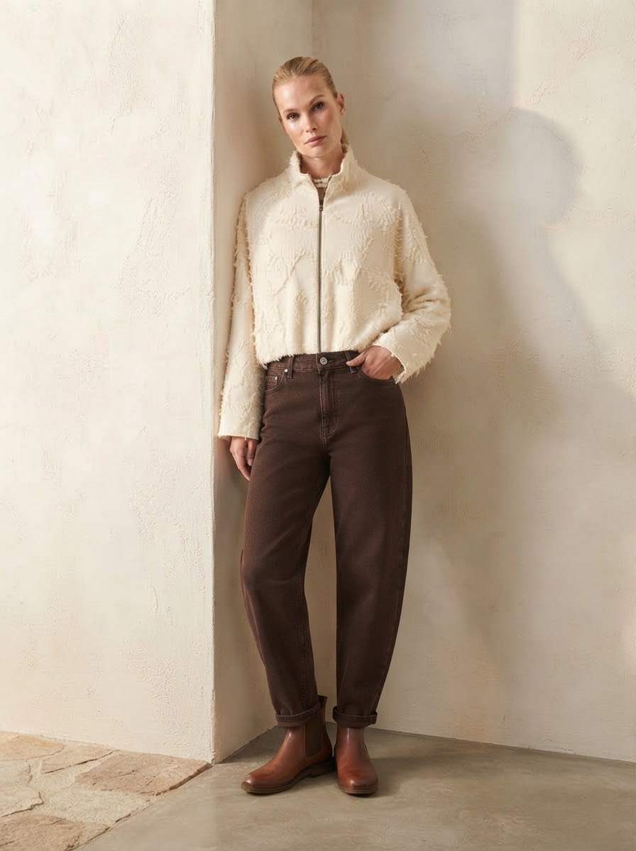 Model wearing chocolate Lucia carrot-shape jeans with cream jacket