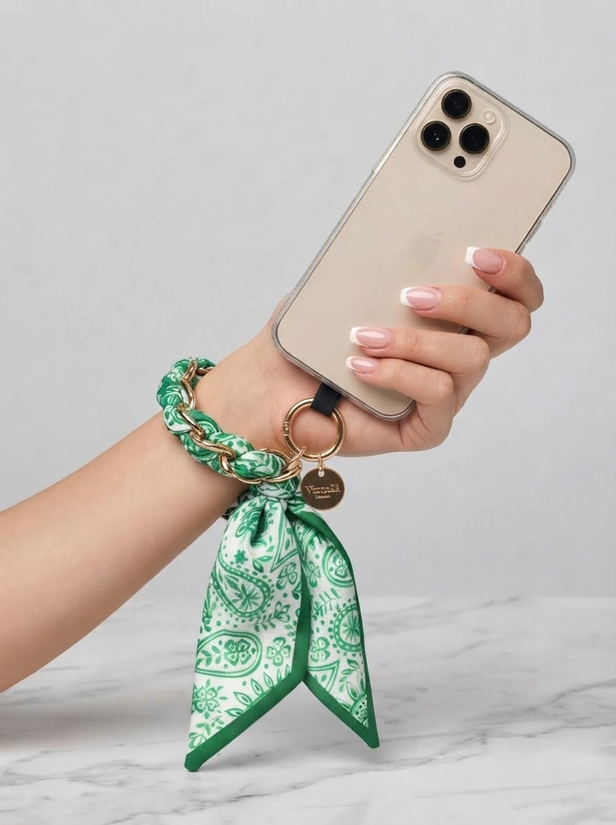 Green Sandi paisley scarf print phone wrist strap worn around the wrist and attached to a phone case