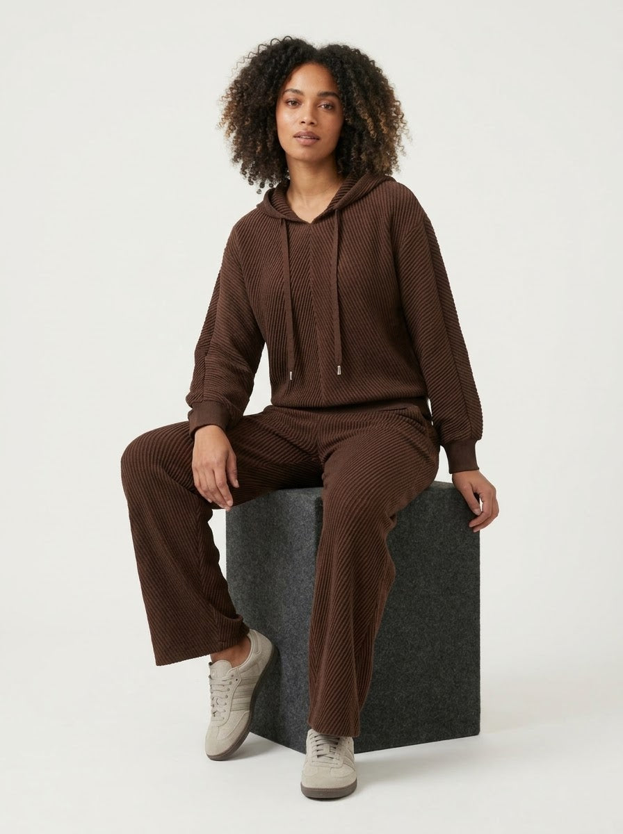 Model wearing chocolate Sunday hooded top, seated three-quarter view