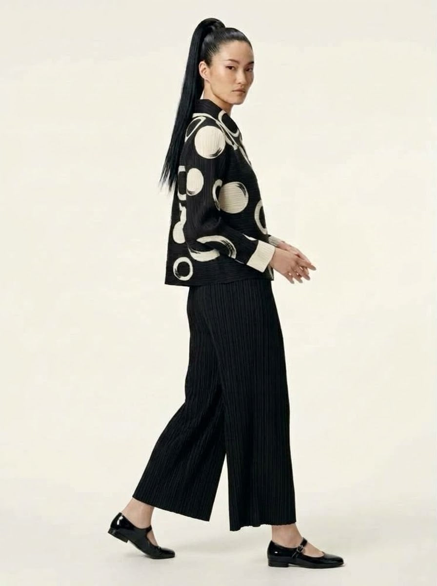 Model wearing Monroe circle print jacket with black Mikaela pleated trousers, side view