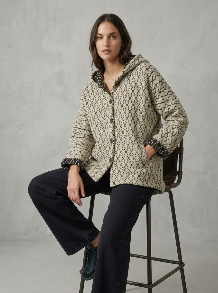 Model wearing Ingrid diamond print hooded jacket in oatmeal, seated view